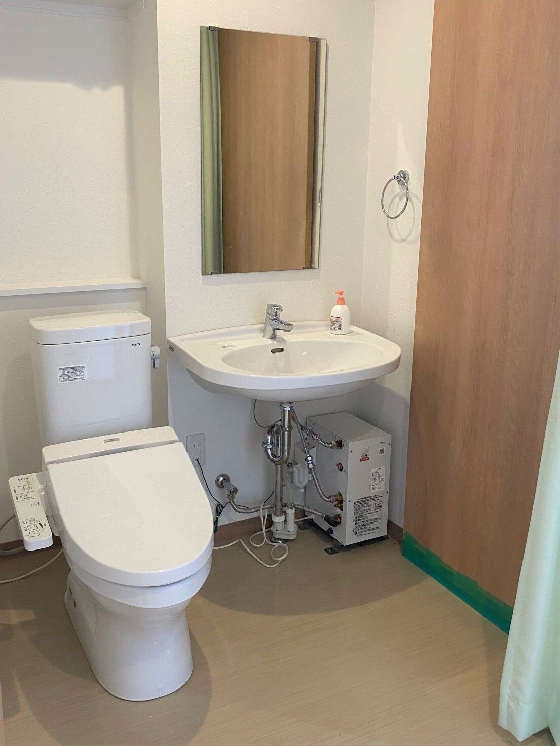 カーテンで開け閉めするタイプのトイレにはトイレだけでなく手洗い場もあり、タオル掛けも壁に設置されている。