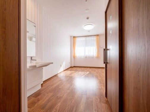 広々としたフローリングの部屋には車いす対応の洗面所が設置され、カーテン付きの窓もある。