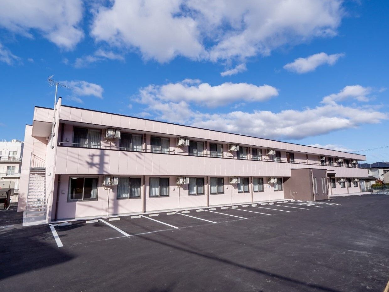日当たりのいい場所に建っている２階建ての建物は横に長く、敷地内には駐車場もある。