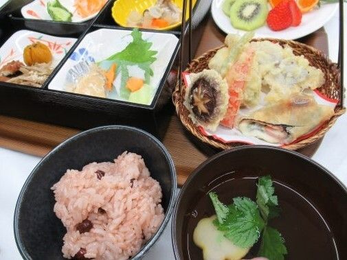 赤飯や天ぷら、吸い物、4つに仕切られた弁当箱にはそれぞれ異なる副菜が入っている。