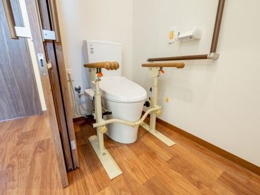 スライド式のドアが設置されたトイレにはオレンジの呼び出しボタンやエル字型の手すりが付いている。