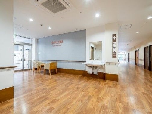 車いす対応の洗面所が設置されている廊下の一角にはテーブルセットもあり、右側には居室が並んでいる。