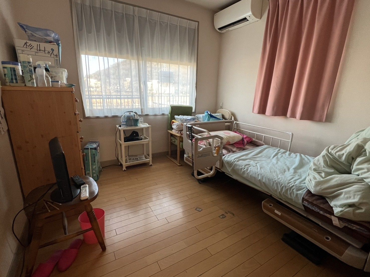 介護用ベッドとエアコン、収納家具が設置されている個室
