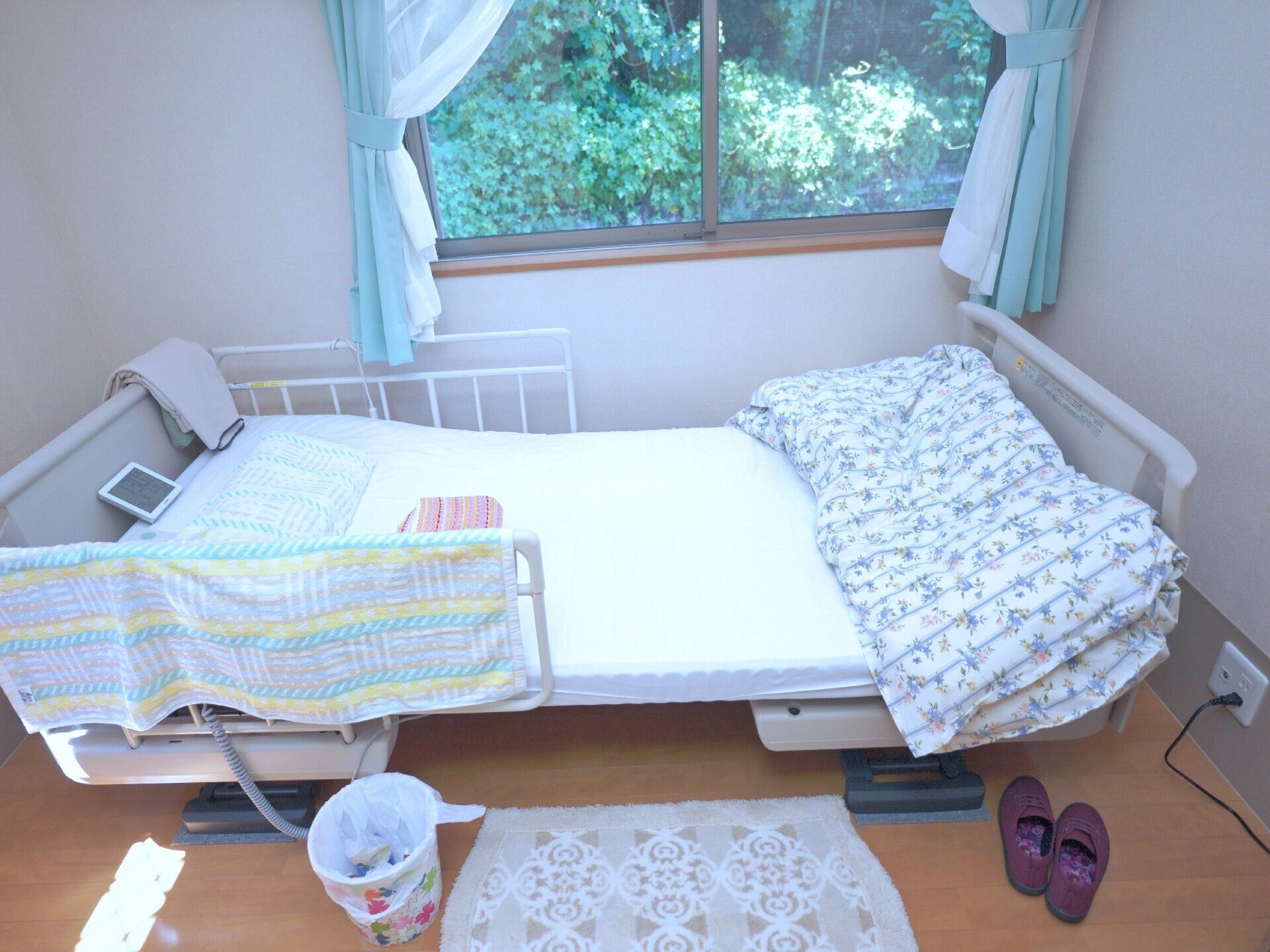 屋外で車いすの高齢の男女が楽しそうに何かを見ている様子。それぞれの車いすは同性の若いスタッフがハンドルを持っていて、近くには福祉車両もある。