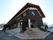 三角屋根が付いた2階建ての建物ん玄関には階段と手すり付きのスロープが付いていて、駐車場もある。