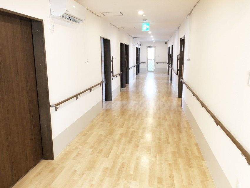 まっすぐな廊下は幅が広く、両サイドに手すりが付き、居室のドアも並んでいる。
