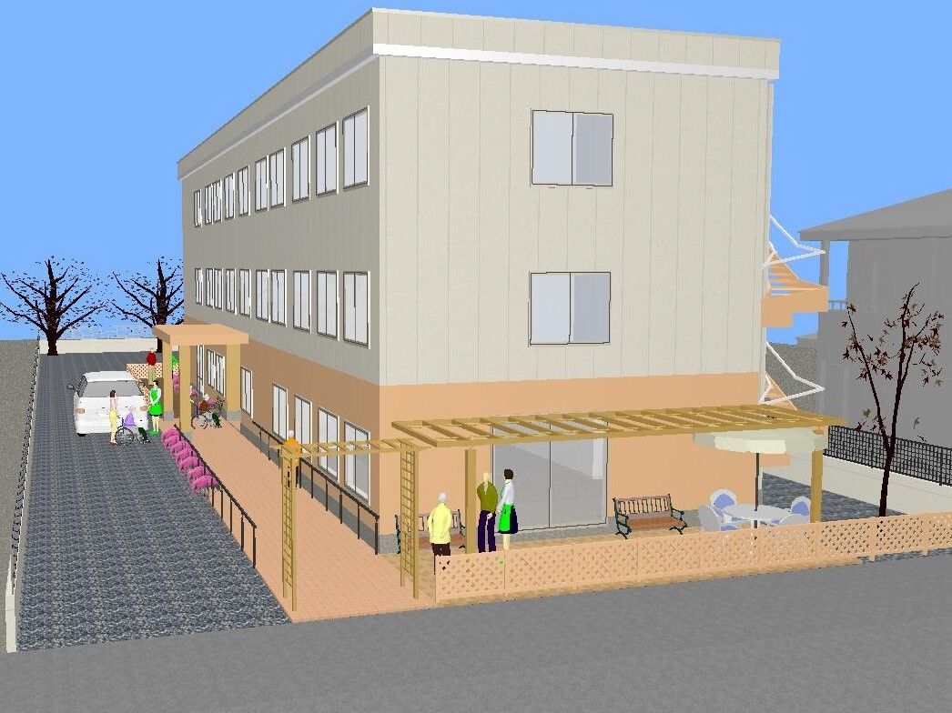 3階建ての建物。1階部分はベージュ、2階と3階は白で玄関の周りの花壇には季節の花が植えられている。