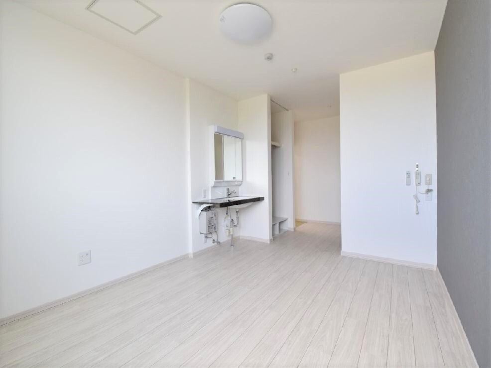 大きな鏡が付いた洗面所が付いた居室。白を基調とした明るい部屋で、緊急通報装置を設置している。