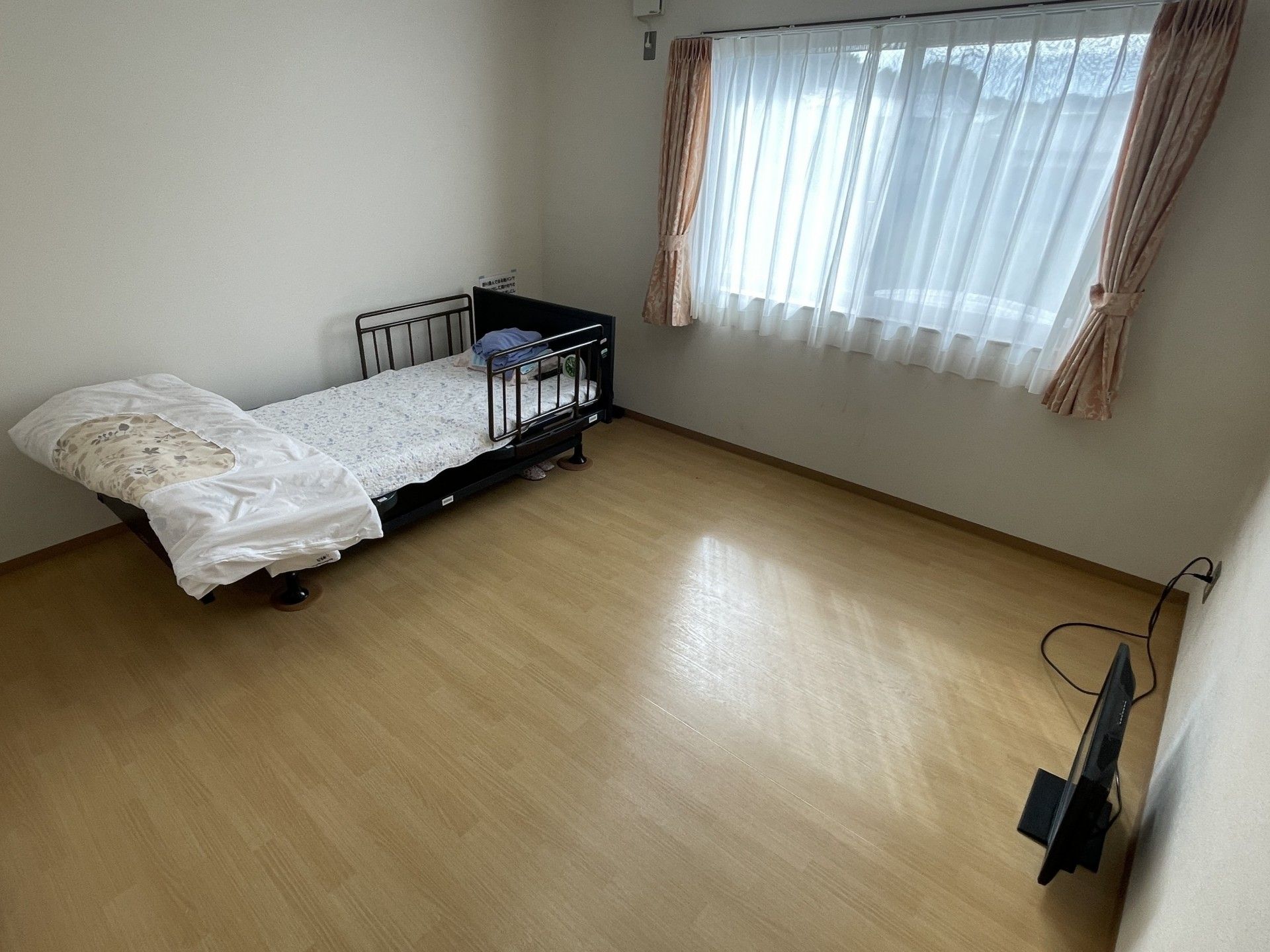 車椅子に座った高齢女性としゃがんで向き合う女性ヘルパー