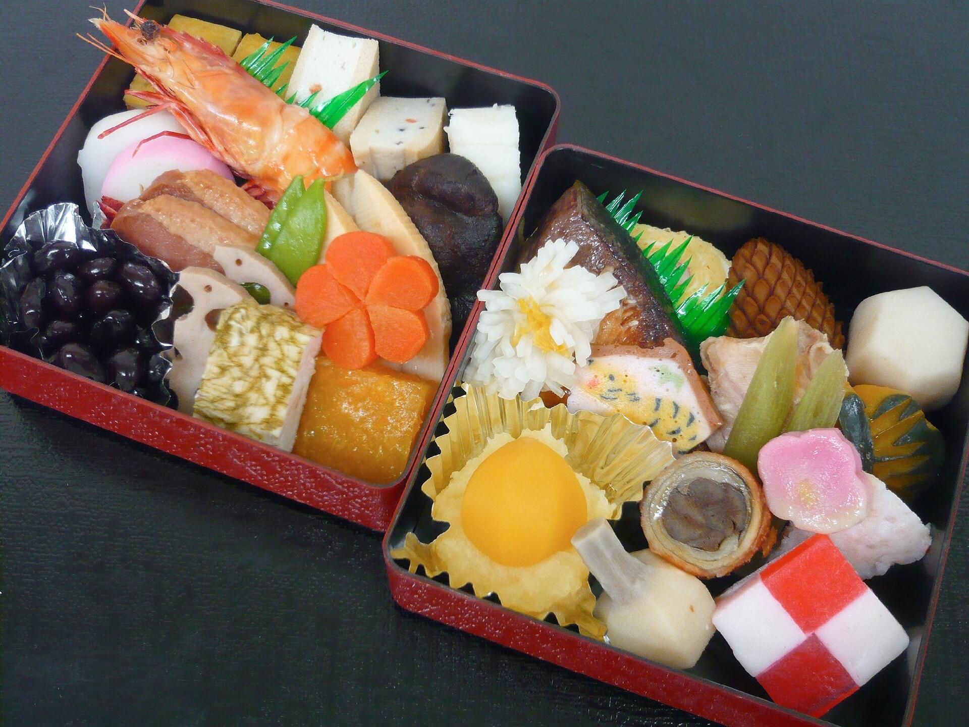 茹でたエビや煮しめ、栗きんとんや紅白寒天、野菜の肉巻きなどが詰められた重箱。おせち風の食事。