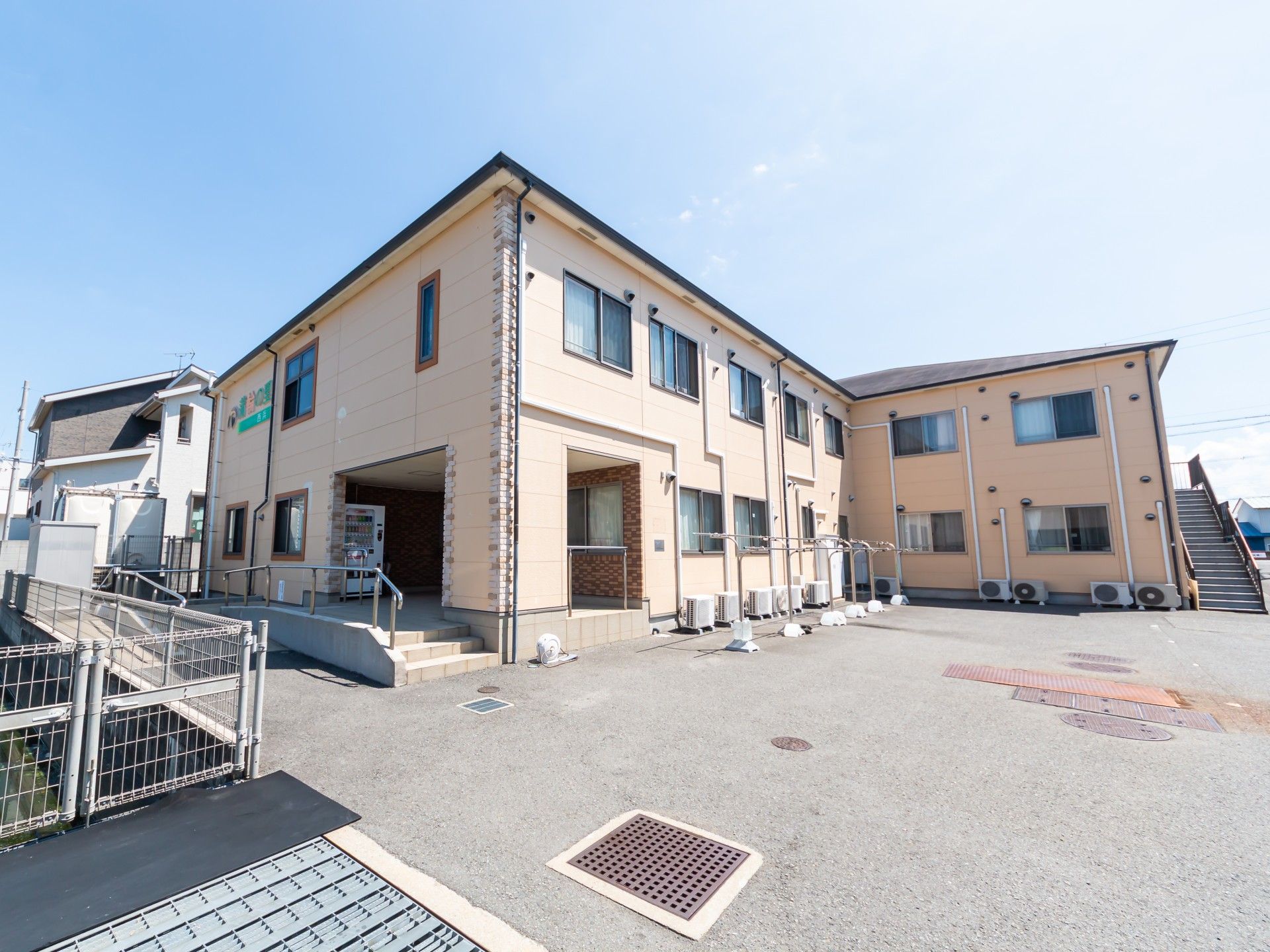 エプロンを付けた女性スタッフに付き添われて散歩を楽しんでいるジャケットを着た高齢女性。