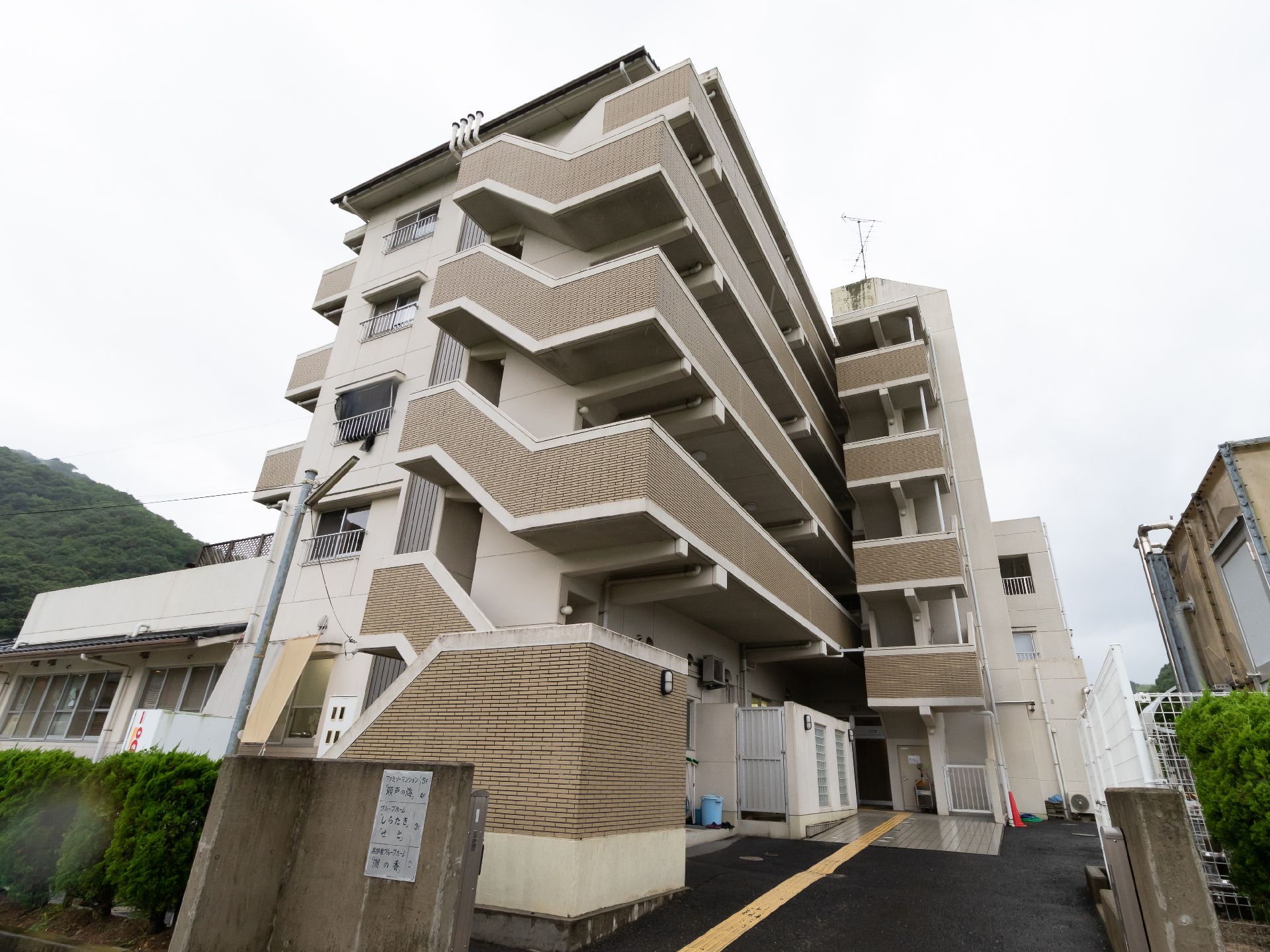点字ブロックが付いたアスファルトに接している５階建てのマンション