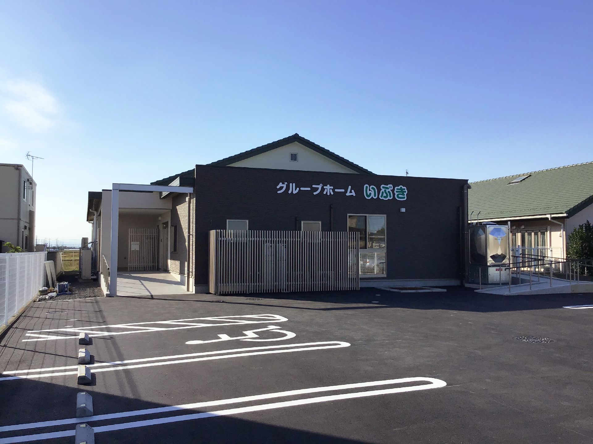 三角屋根が付いた平屋建ての建物。自動ドアが設置された玄関には屋根も付き、駐車場も完備されている。