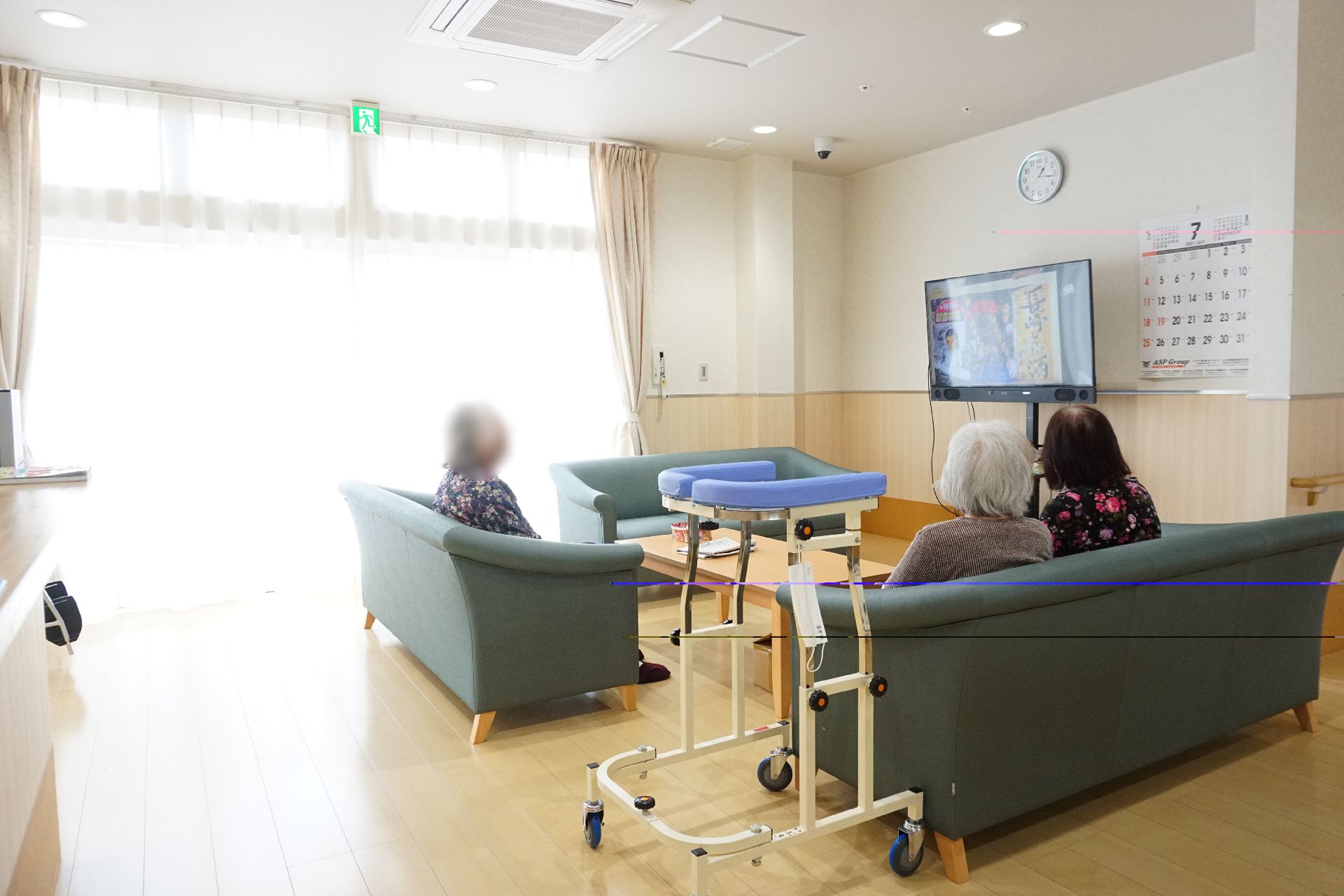 窓から陽光が入り、壁掛けテレビが設置されているリビング