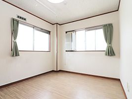 広いフローリングの居室にはカーテンが付いた大きな窓が二つあり、日当たり良好。照明もある。