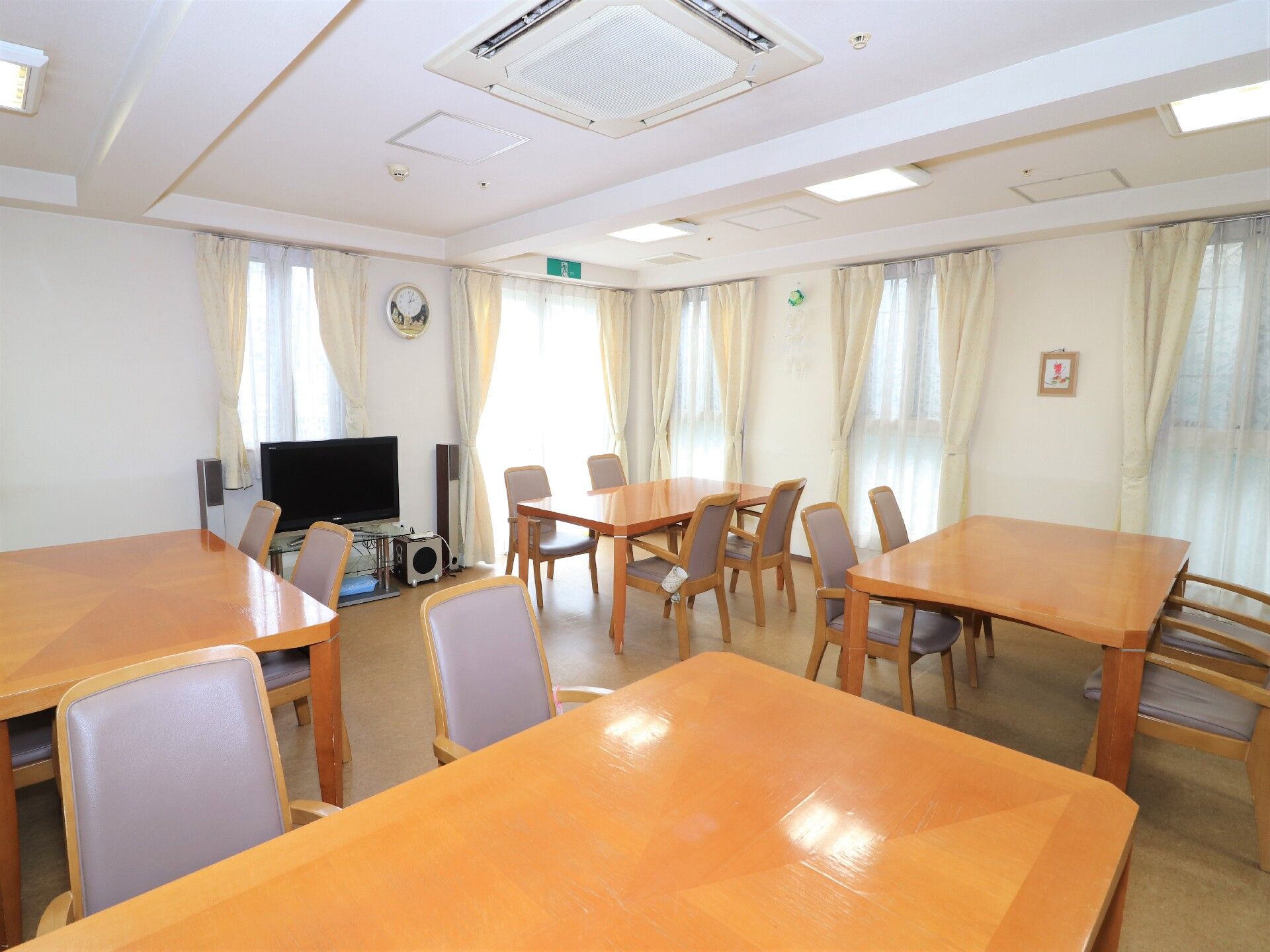 大きなテレビがついた食堂には4人掛けの木製テーブルが複数置かれ、日当たりも良好。壁には絵画や時計が飾られている。