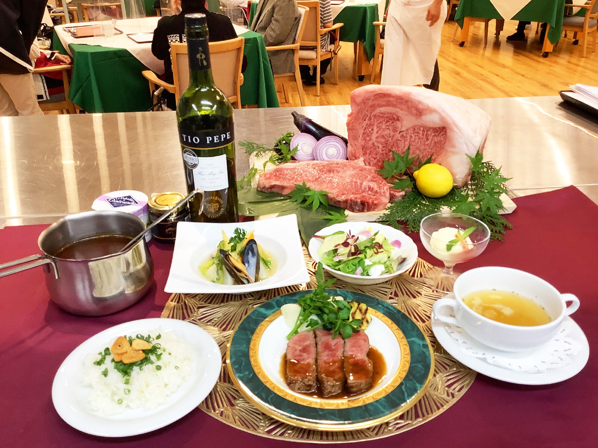 牛肉のステーキをメインに、ガーリックライスやスープ、サラダやデザートなどが並んでいるテーブル。