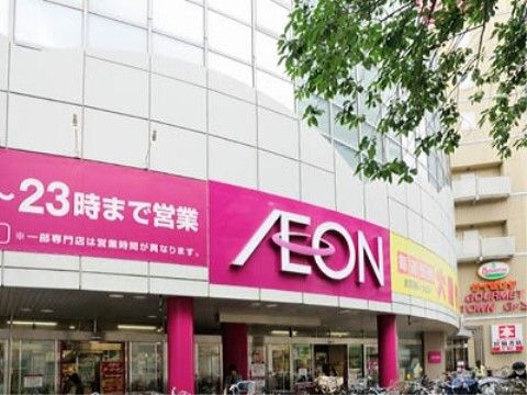 大型のスーパーマーケットの建物の外観で、建物の壁は白色系である。壁面には赤地に白色で店名が表示されている。