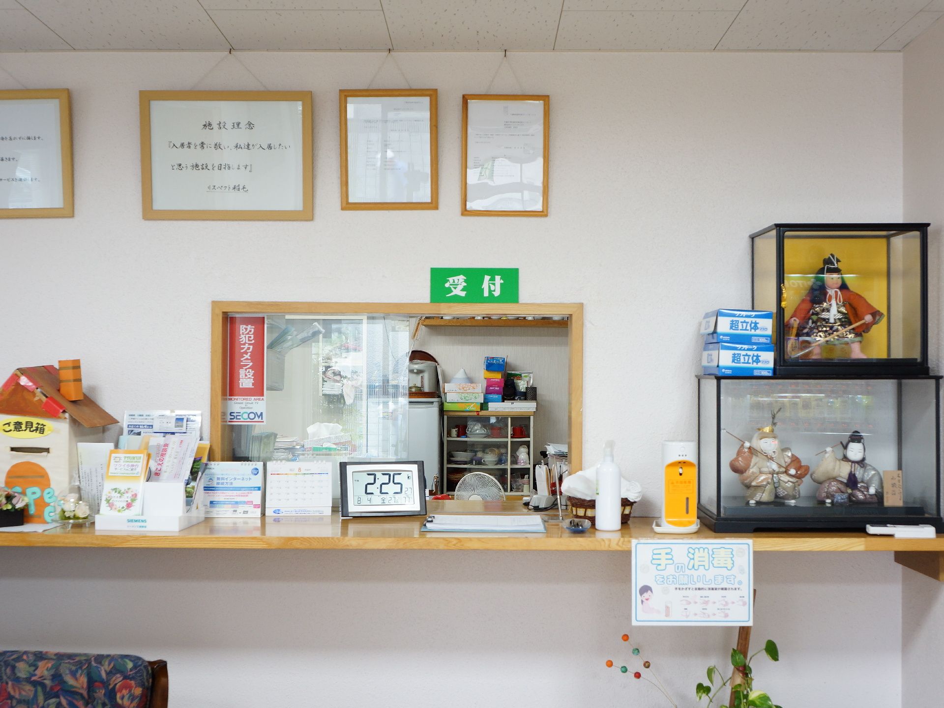 受付を正面から写した様子。小さな小窓から中ら少し見えている。カウンターにはものがいろいろと置かれている。