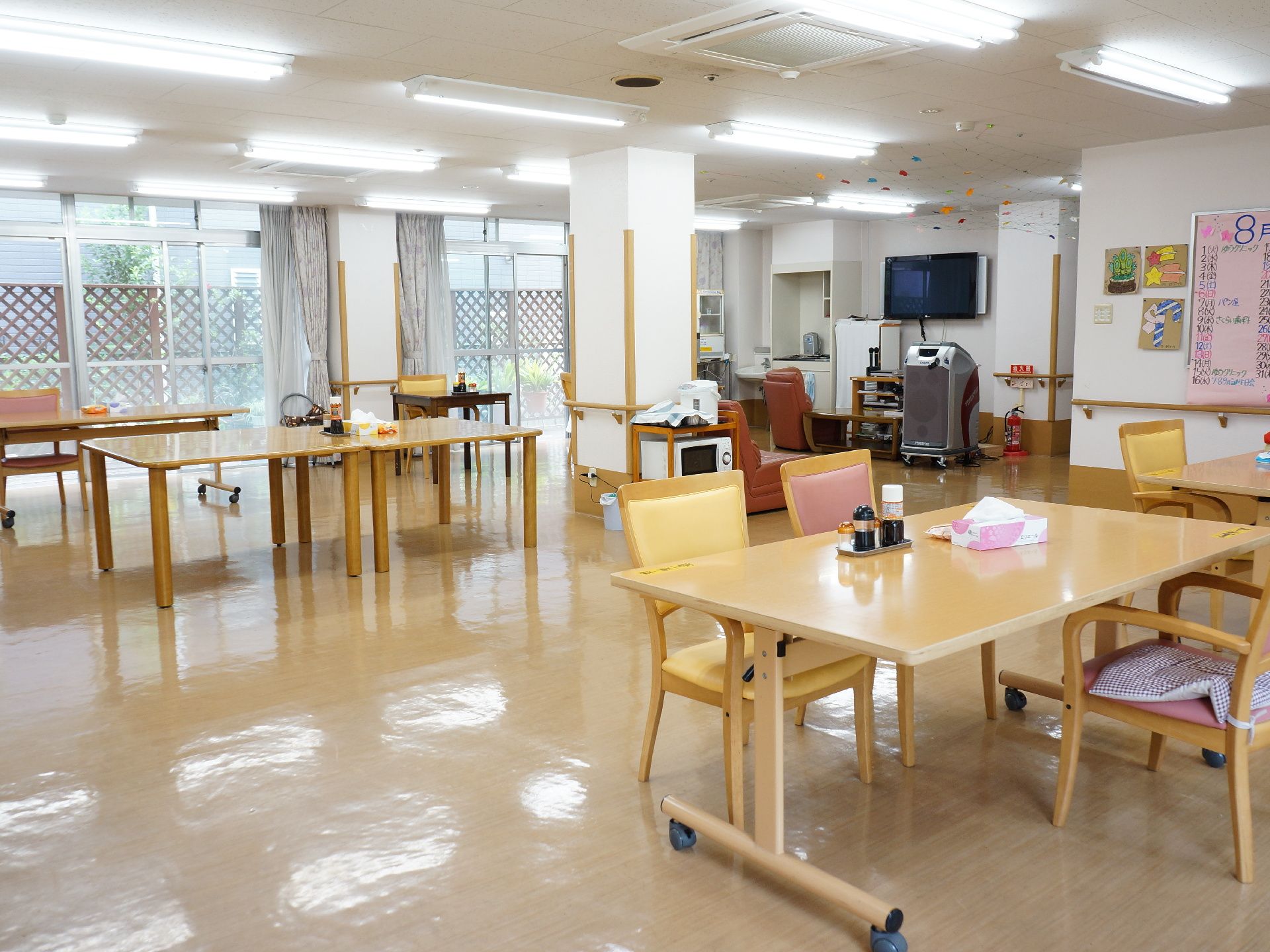 食堂・談話室の様子。とても広くて、大きなテーブルが、いくつか置かれている。一部のテーブルの脚にはキャスターが付いている。