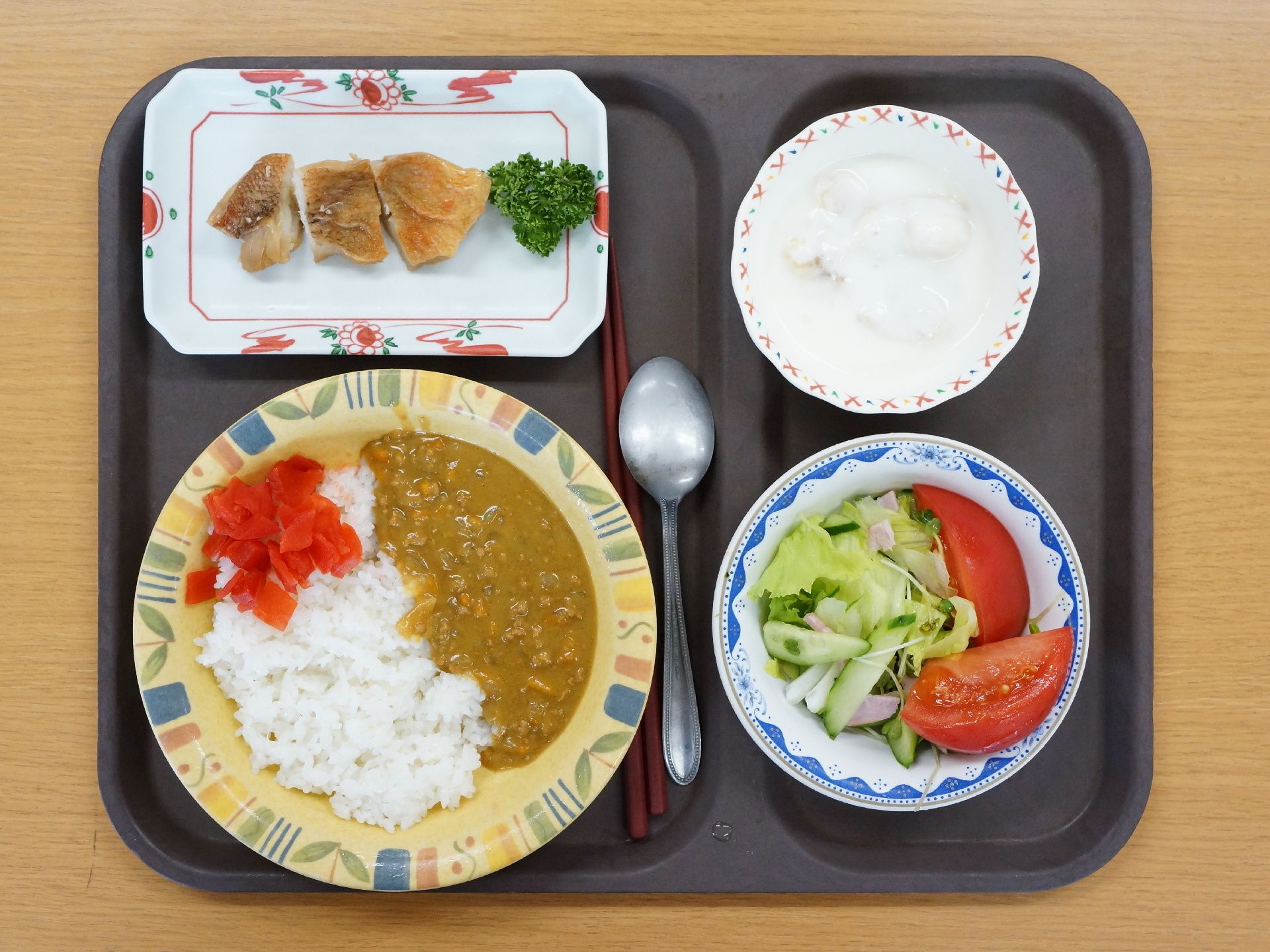 食事の写真。メイン料理はカレーライス。福神漬けが添えられている。他は、チキンソテー、トマト入りのレタスサラダ、ヨーグルト。