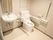 手すりや背もたれが付いた広いトイレは白を基調としていて、大きな鏡が付いた手洗い場もあり、介助するスタッフが入れるスペースもある。