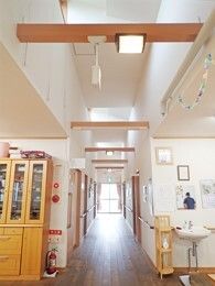 車いす対応の洗面所や扉付きの棚が置かれた共有スペースからまっすぐな廊下が続いていて、手すりも設置されている。