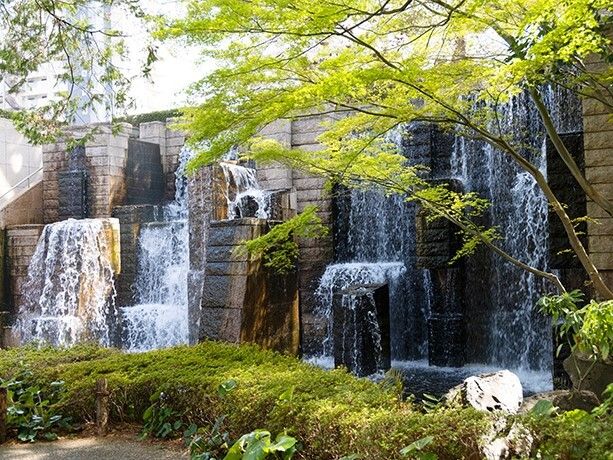 人工の滝には水が勢いよく流れていて、周りには草木が植えられている。