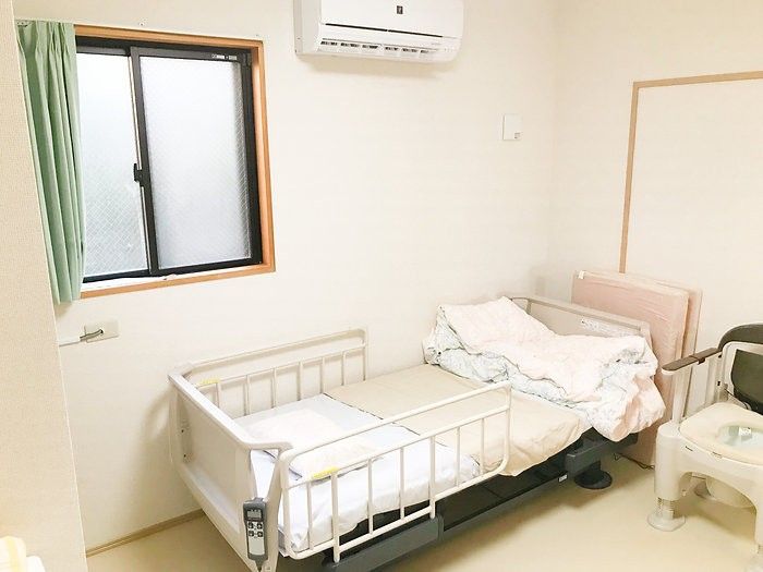 車椅子に座っている高齢女性の手を取る女性ヘルパー