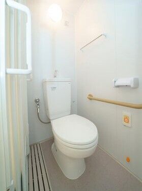 呼び出しボタンや手すり、タオル掛けが付いたトイレはシンプルなデザイン。ドアはスライド式。