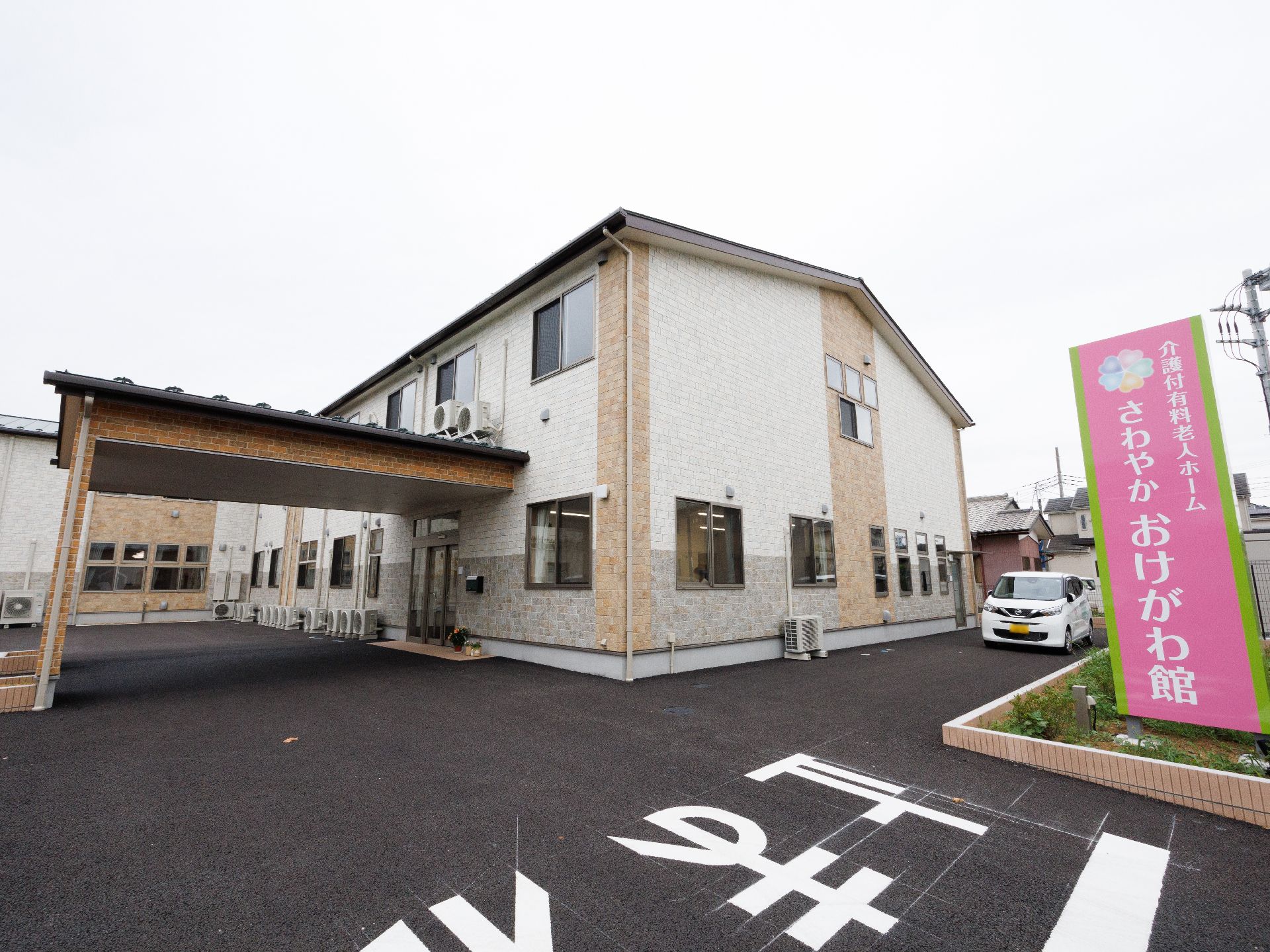アスファルト上に立地している白い外観で２階建ての建物