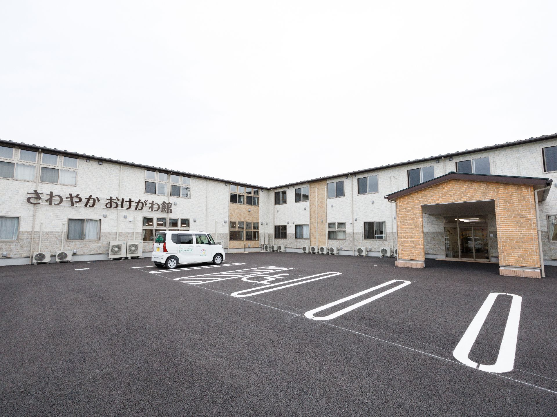 広い駐車場に隣接した白い外観で２階建ての建物