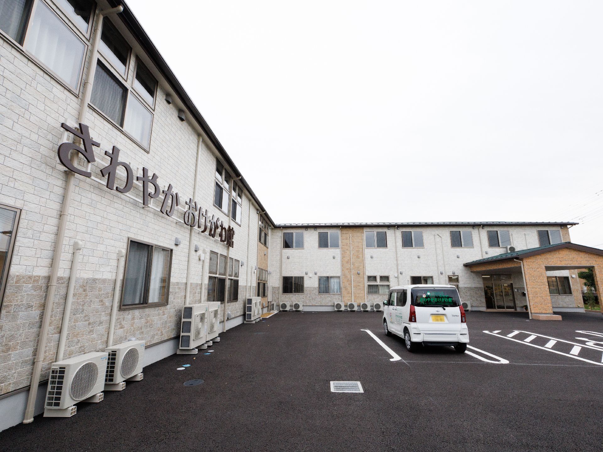 広い駐車場に隣接した白い外観で２階建ての建物