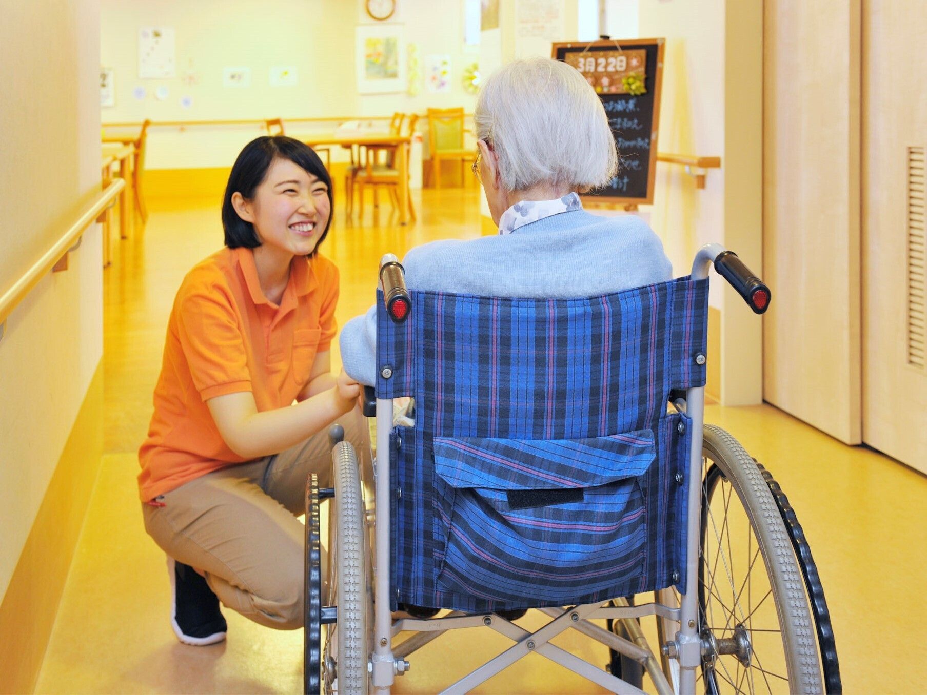 車椅子に座っている高齢者を介助する女性スタッフ