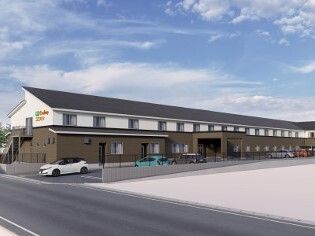 駐車スペースもある２階建ての建物。白とブラウンの外壁に黒い三角屋根が付き、家庭的な雰囲気が漂う和風の住まい。