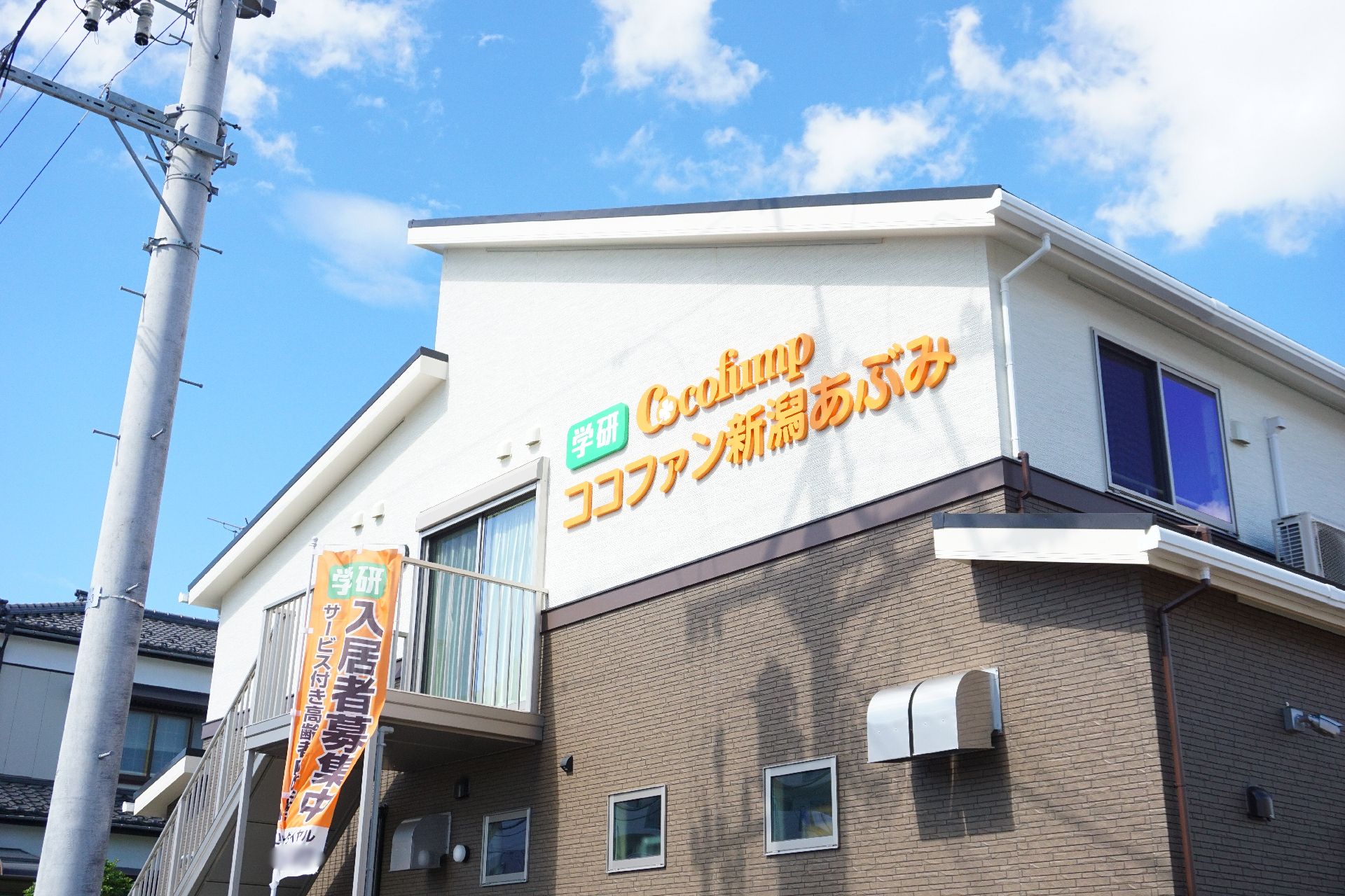 2階建てで、白と茶の落ち着いた色合いが特徴の施設の外観