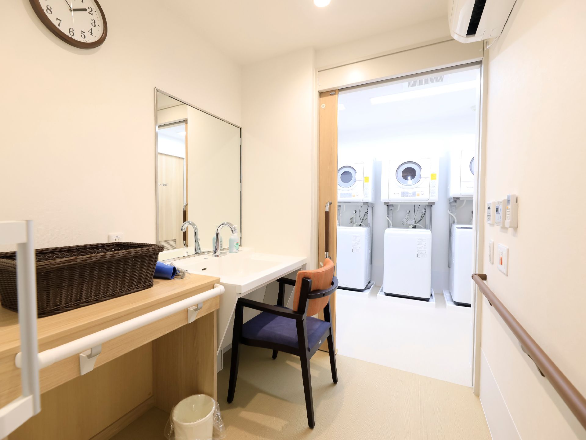 隣の部屋に洗濯機と乾燥機が多数並んでいる浴室の脱衣場