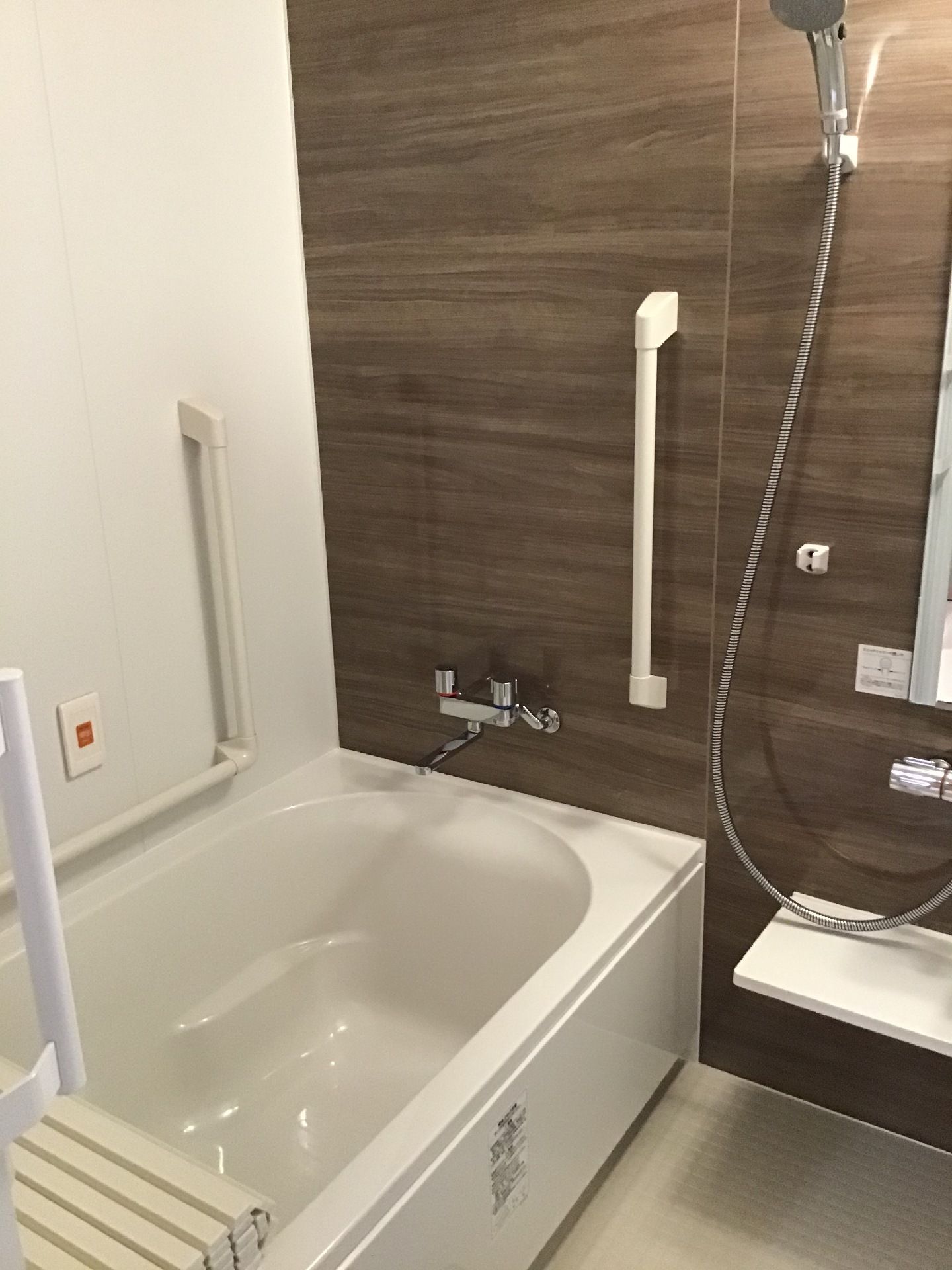 オレンジの呼び出しボタンが設置された一人用の浴槽が設置された浴室には、手すりやシャワーもある。