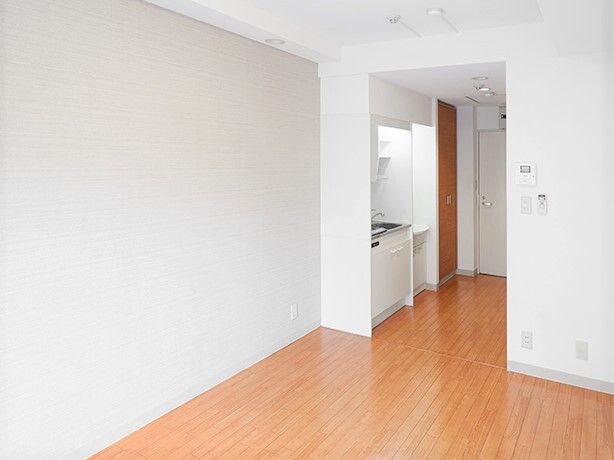 白い壁紙が貼られたシンプルな部屋はフローリングのフロア。キッチンや洗面所も付いている。