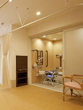 ベージュ系の浴室内にはダークブラウンの手すりが設置され、シャワーやシャワーチェアもある。