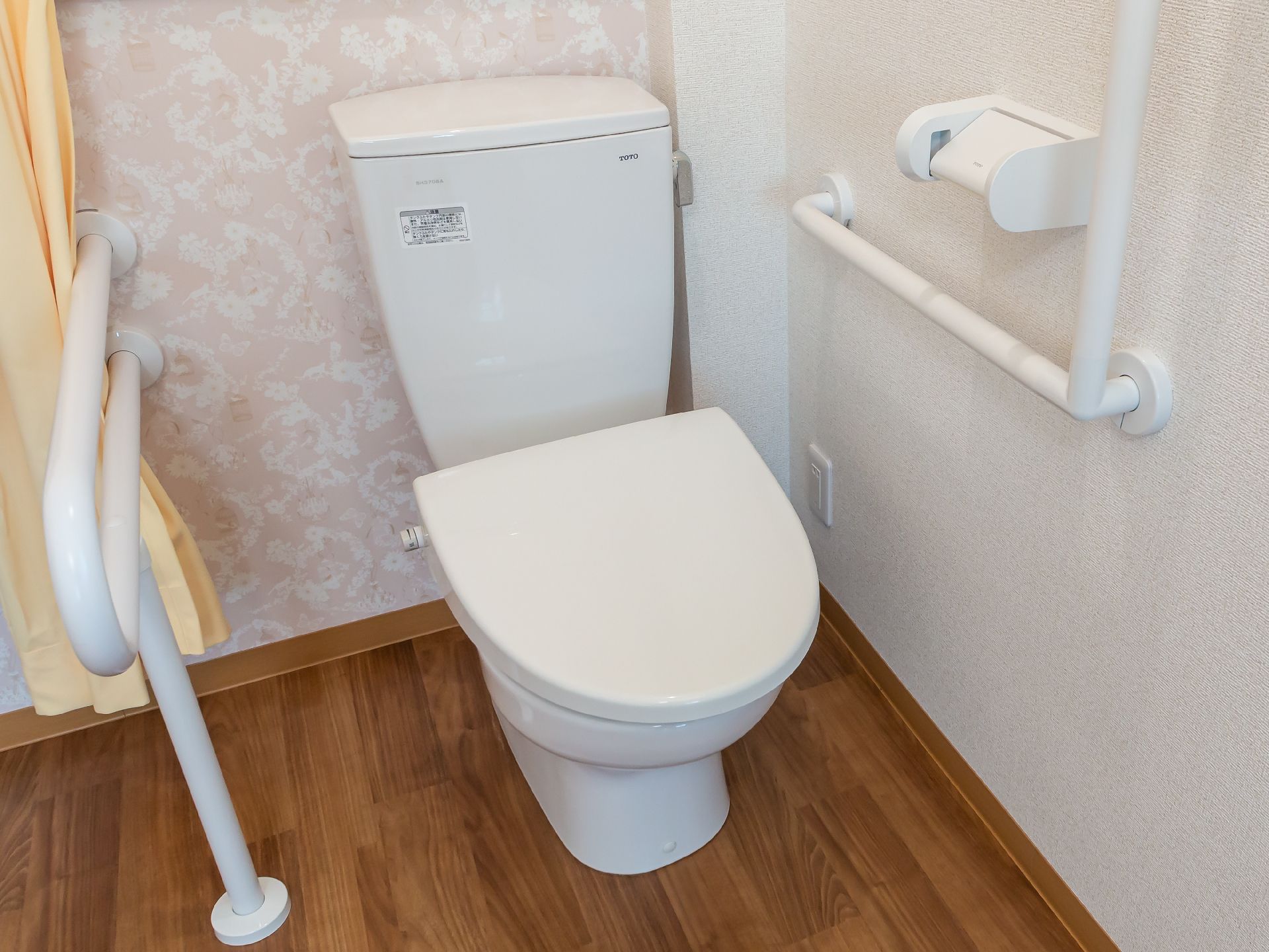 白い手すりに囲まれた蓋が閉まった洋式便器
