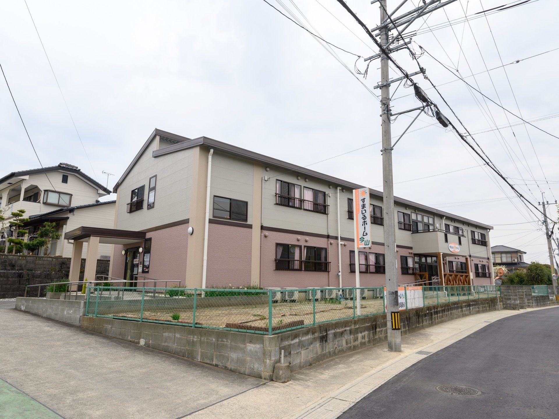 住宅街に施設がある。道路から少し嵩上げした場所に建物があり2階建てである。腰高窓が並んでおり、建物の端に玄関がある。