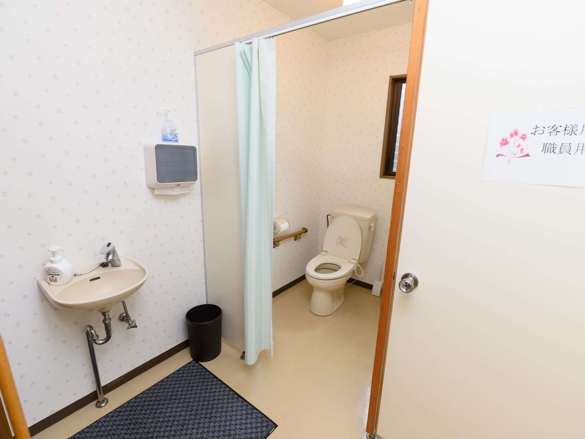 来訪者様とスタッフ用のトイレがある。カーテンで目かくしをできるようになっている。ペーパーホルダーがついている。