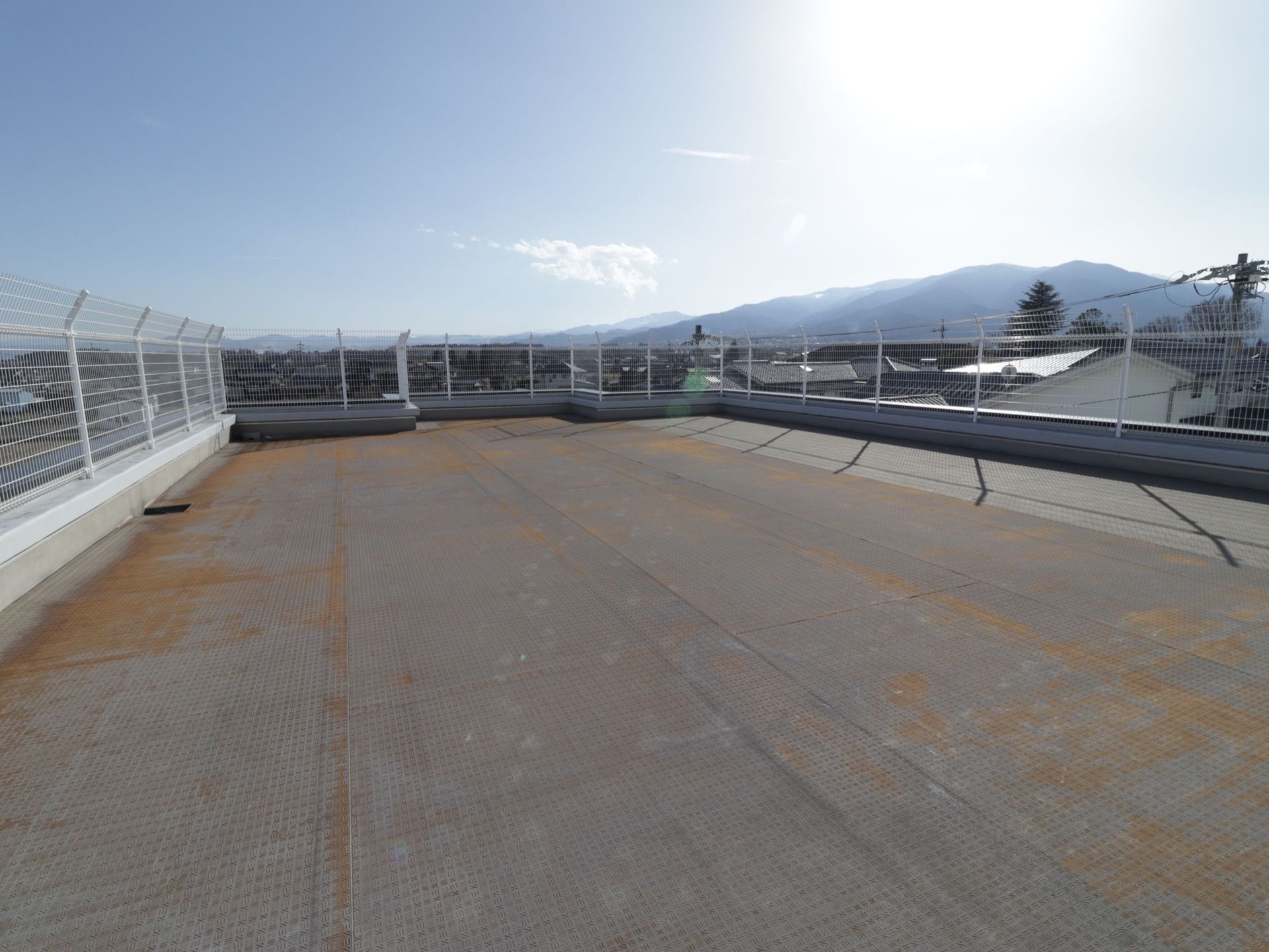 高さのある白いしっかりした柵で周りを囲まれている。建物の周辺には大きな建物がなく、広い空を眺めることができる。