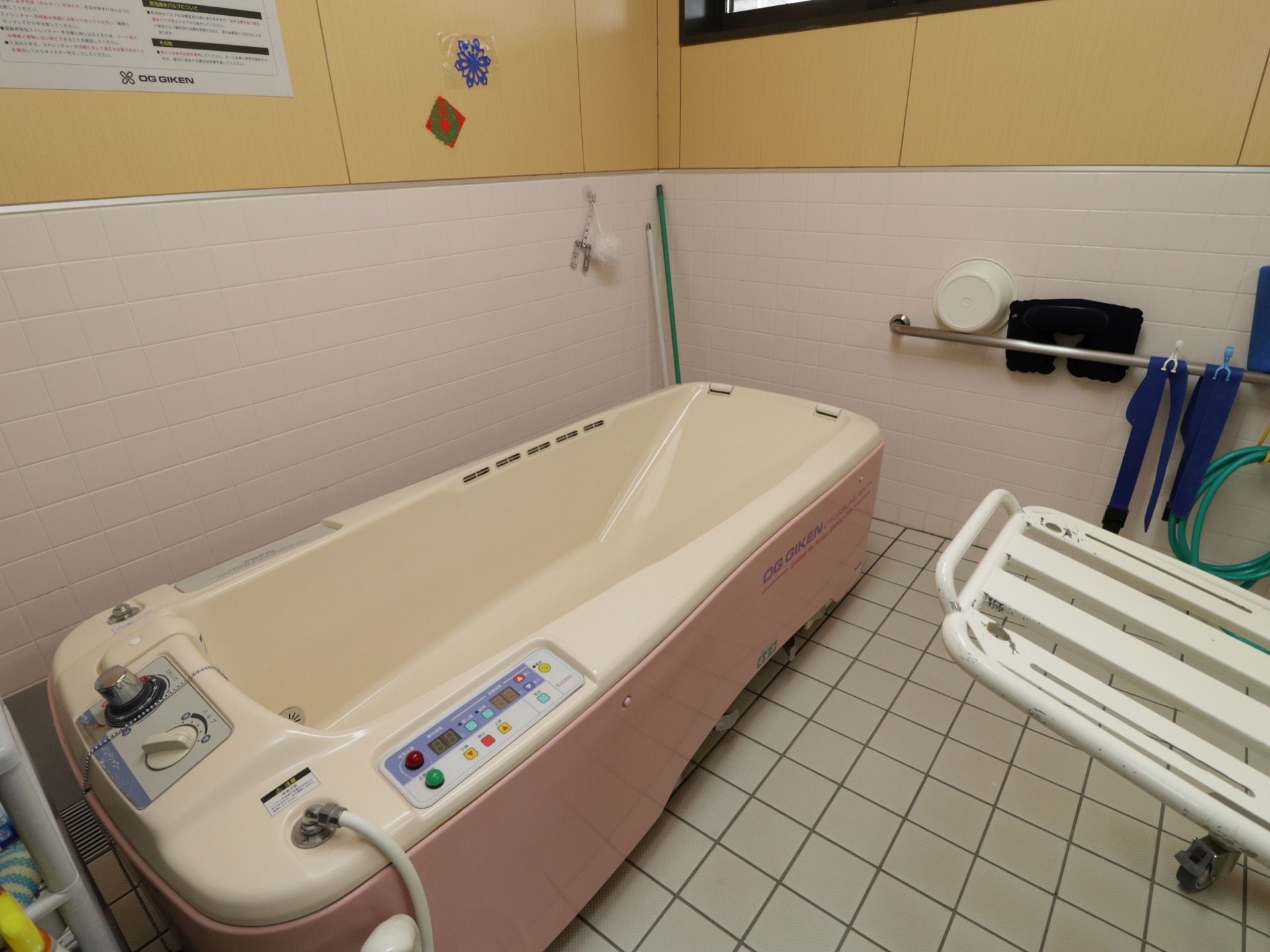 介助用の浴槽が設置されている。手足の伸ばして入浴できる大きさがある。壁に手すりが取りつけられている。桶や滑り止めが用意されている。