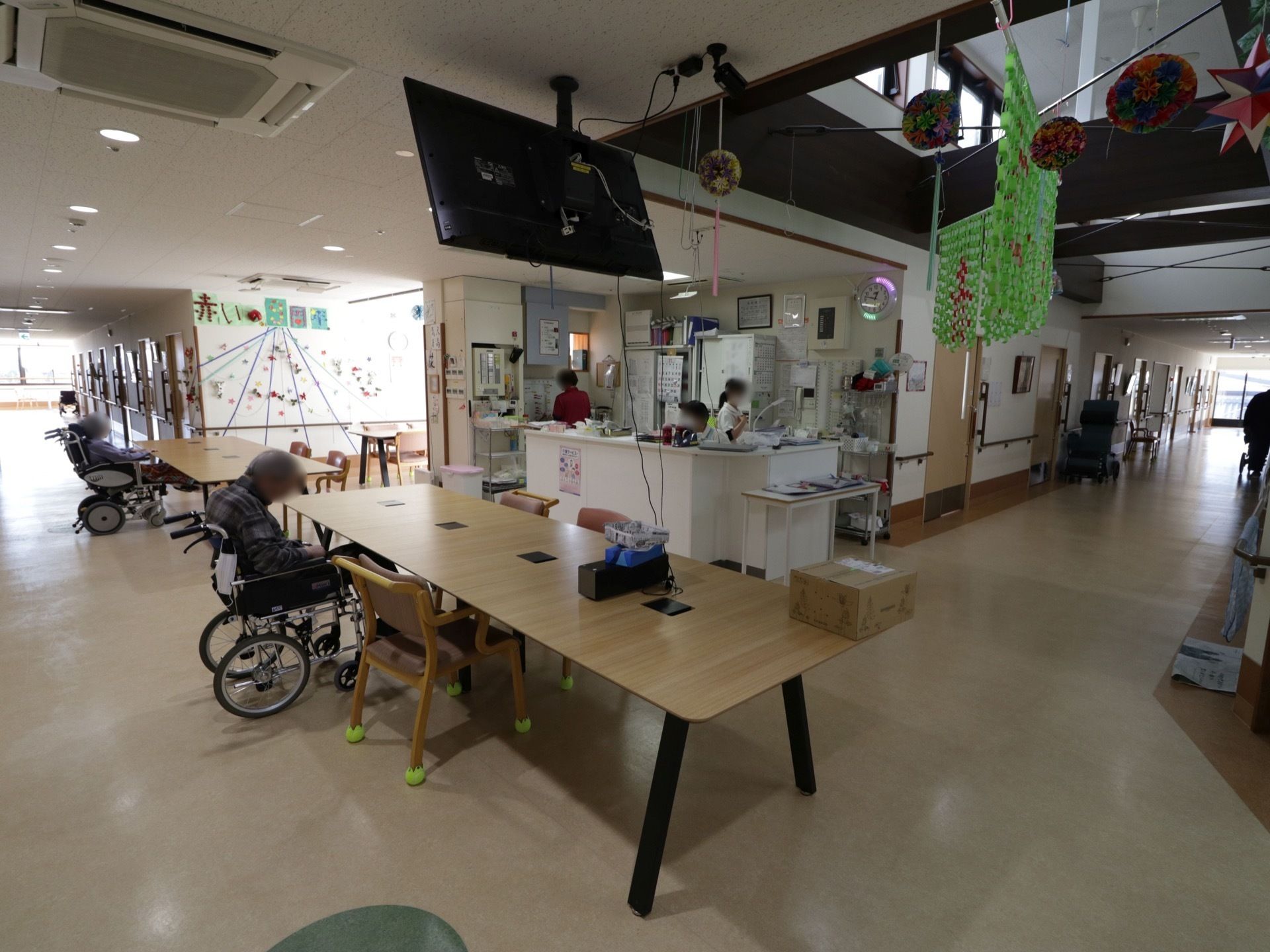 事務室の前にテーブルが並んでおり、その頭上にテレビが取りつけられている。広々としており、障害になるものが置かれていない。