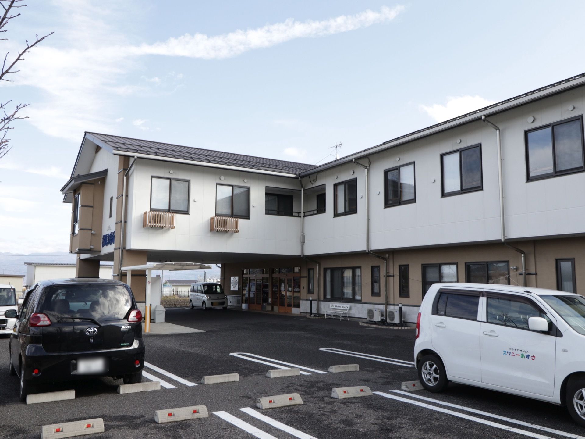 施設の前に広い駐車場が用意されている。２階建てで、たくさんの窓が設置されている。タクシー乗り場がある。
