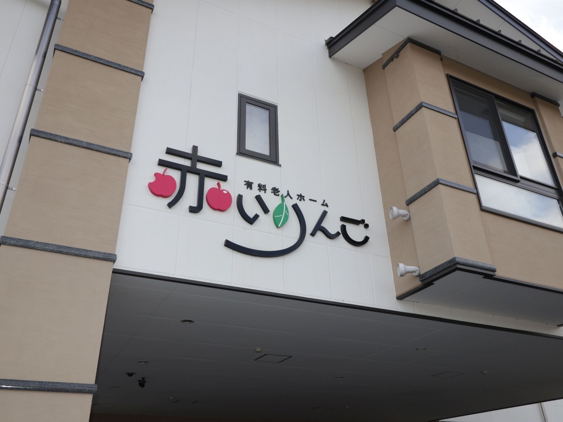 建物の正面左側に施設名が大きく書かれている。黒を基調とした字体の中に、リンゴと葉っぱがあしらわれている。