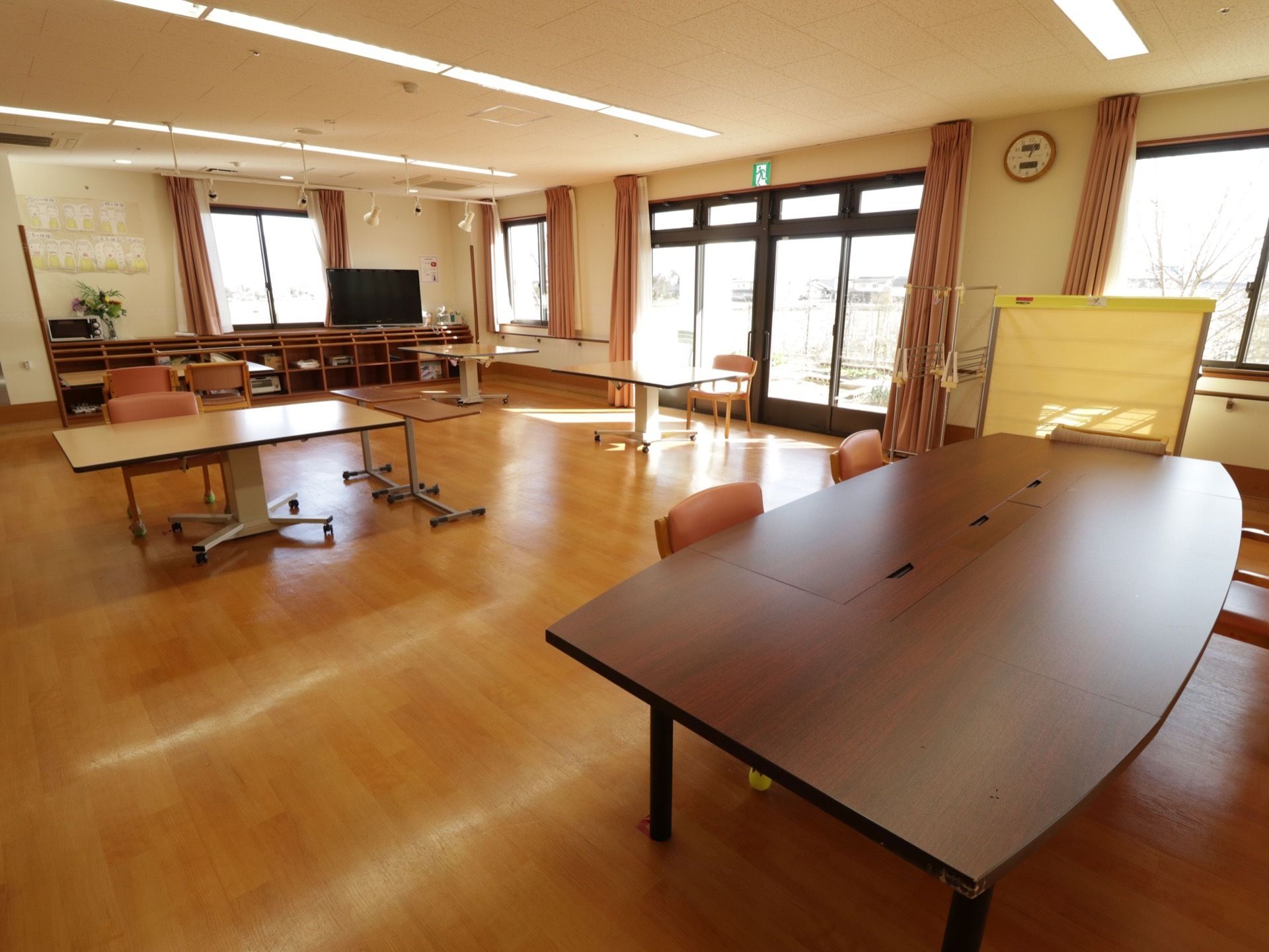 日当たりが良く、開放的なスペースになっている。テーブルと椅子がいくつも用意されている。奥にはテレビが設置されている。