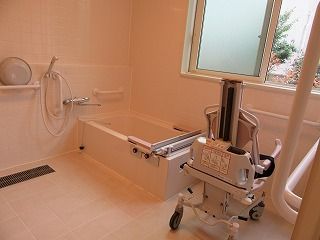 シャワーや手すりが付いた浴室は洗い場が広く、浴槽にはレールが付き、リフトが置かれている。